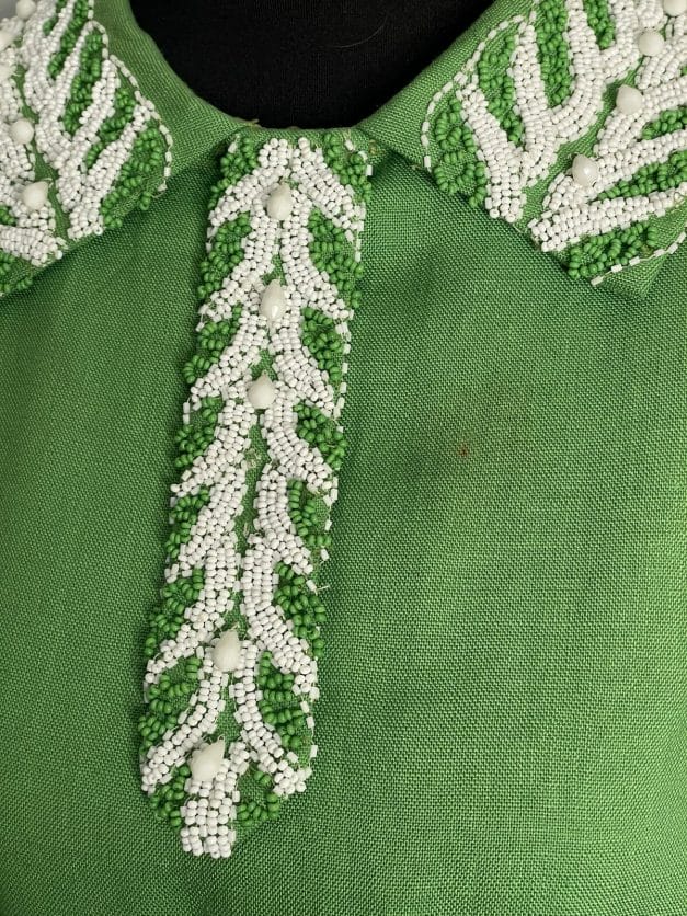 closeup of green and white beads on green linen dress