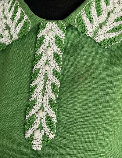 closeup of green and white beads on green linen dress